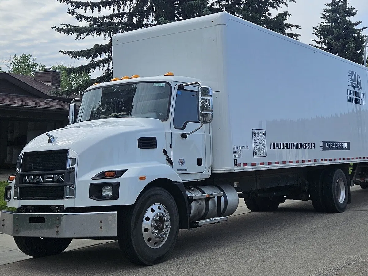 Our white Mack 5-ton moving truck, with our name on the box, parked outside a house
