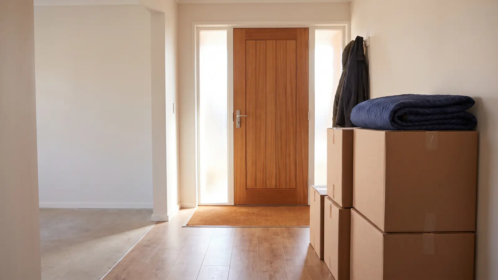 Moving checklist, final week: sealed boxes stacked by the front door, a folded moving blanket on top