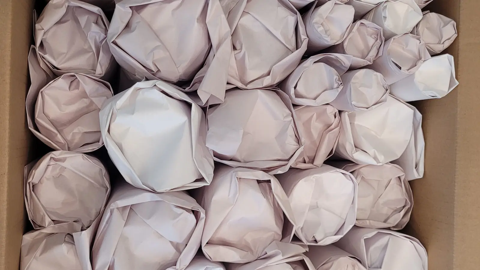 Packing services in Calgary: kitchen items wrapped one by one in packing paper and packed snugly in a box
