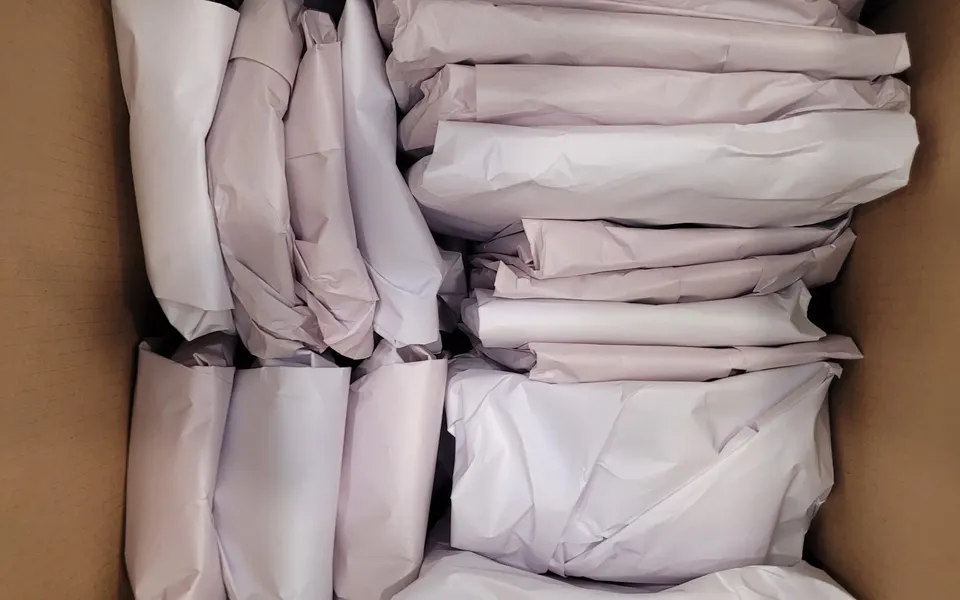 Plates and kitchen items wrapped one by one in packing paper and packed upright in a box