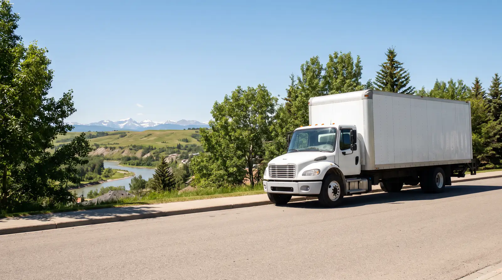 Movers in Cochrane: a plain white box truck parked on a sunny street lined with leafy trees