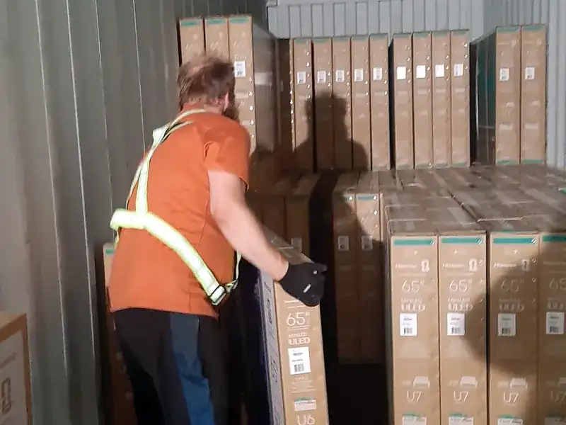 Container unloading for a Calgary-area warehouse: our crew member unloads TV cartons by hand from a floor-loaded container