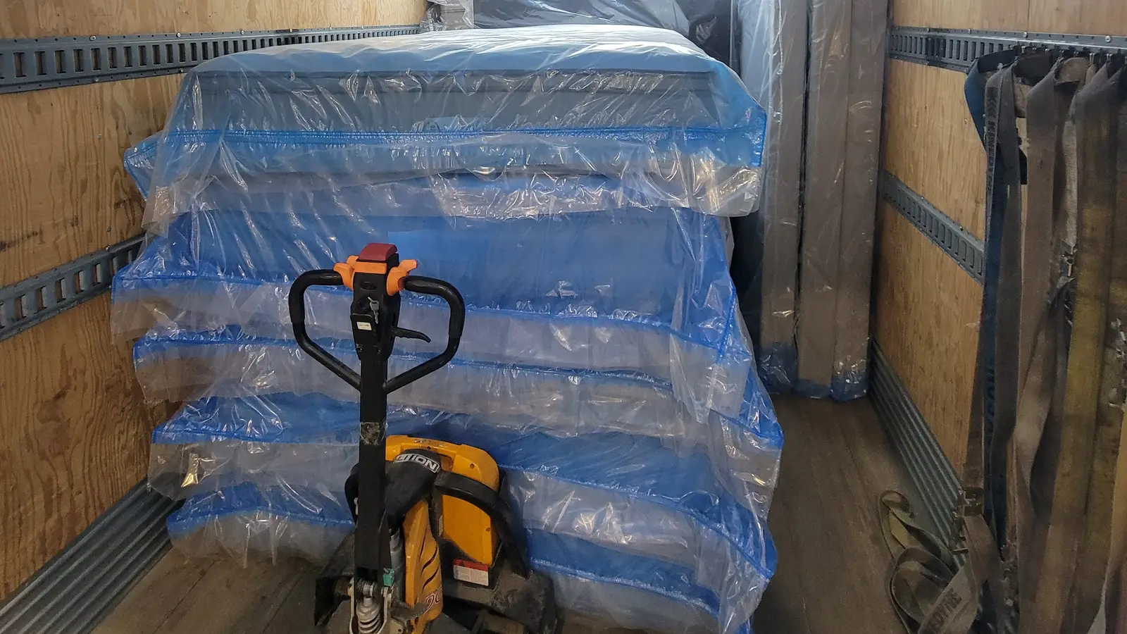Pallet delivery in Calgary: plastic-wrapped pallets and an electric pallet jack in the cargo box of a straight truck